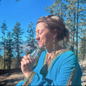 Heidi Rasmussen holding a crystal outdoors among pine trees