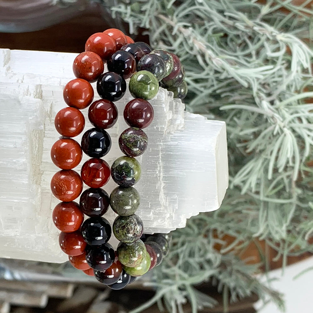 Red jasper, black stripe agate and dragon’s blood bead bracelets stacked on a selenite tower