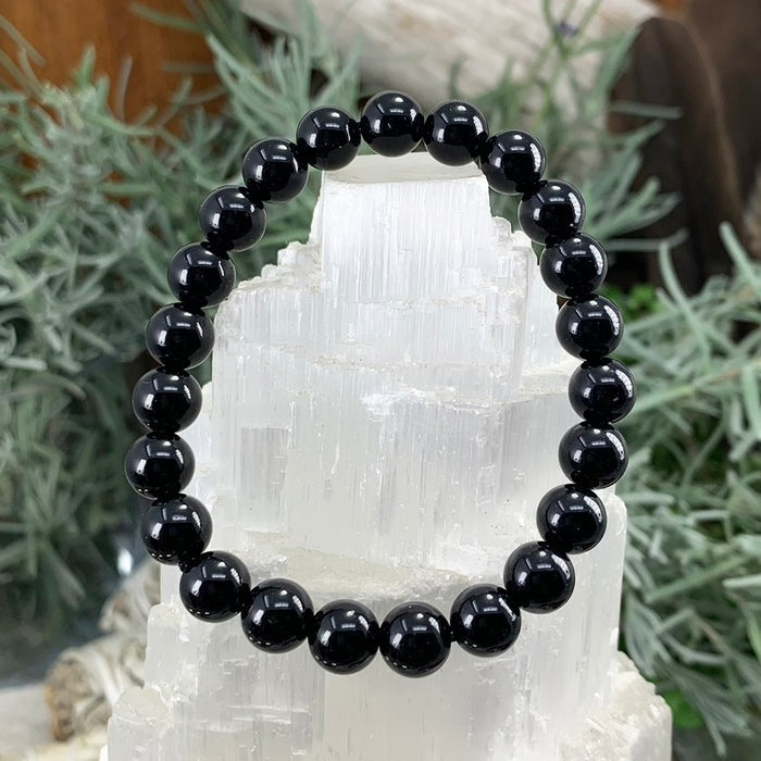 Black obsidian round bead bracelet on a white selenite block