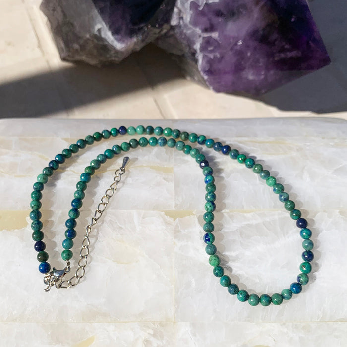 Phoenix lapis beaded necklace in deep green and blue on a selenite slab