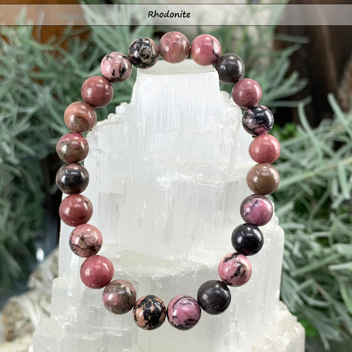 Pink and black rhodonite bead bracelet on a selenite tower